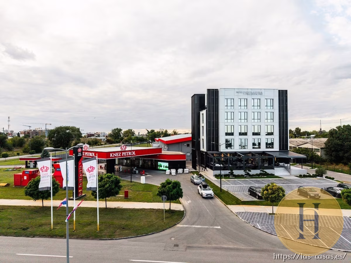 Hotel Premium moderno junto a una estación de servicio Knez Petrol, con coches aparcados y banderas promocionales.