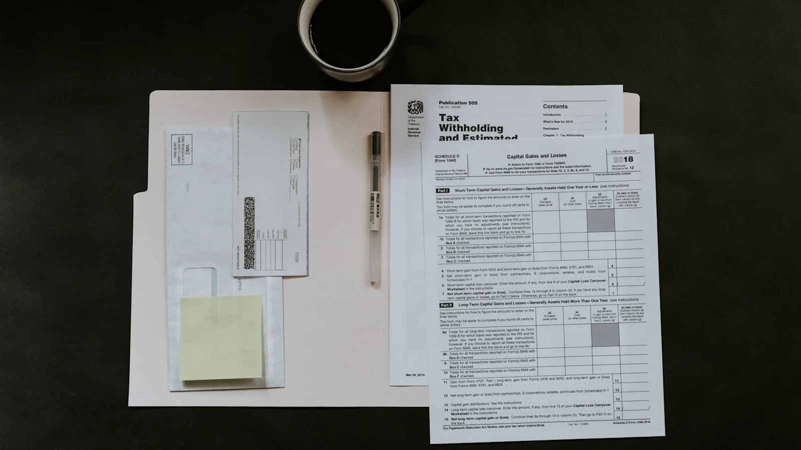 Documentos fiscales estadounidenses (Formulario 1040, Schedule D) sobre una carpeta, junto a un bolígrafo, notas adhesivas y